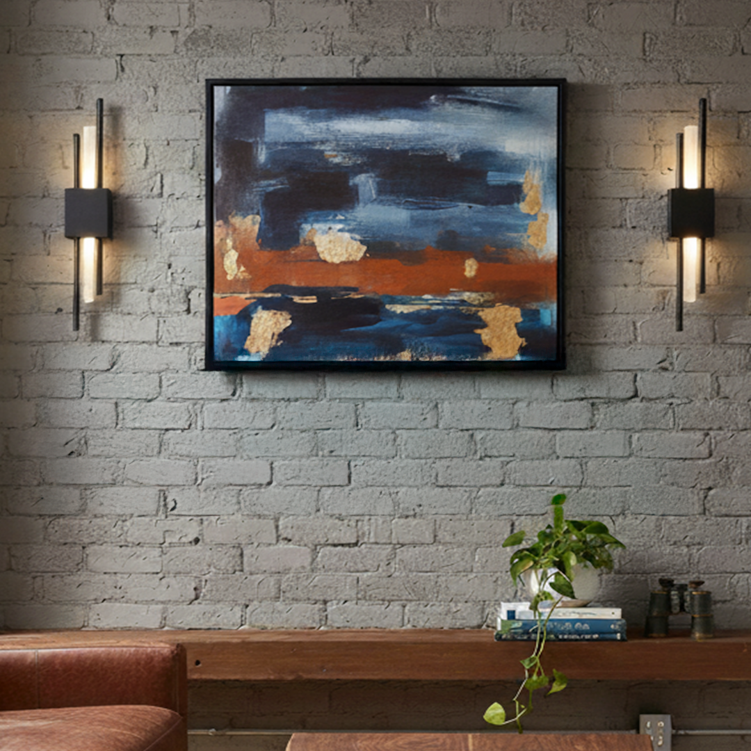 Two black AMBIO battery wall sconces lit either side of an abstract painting on a white brick wall, Mistiva