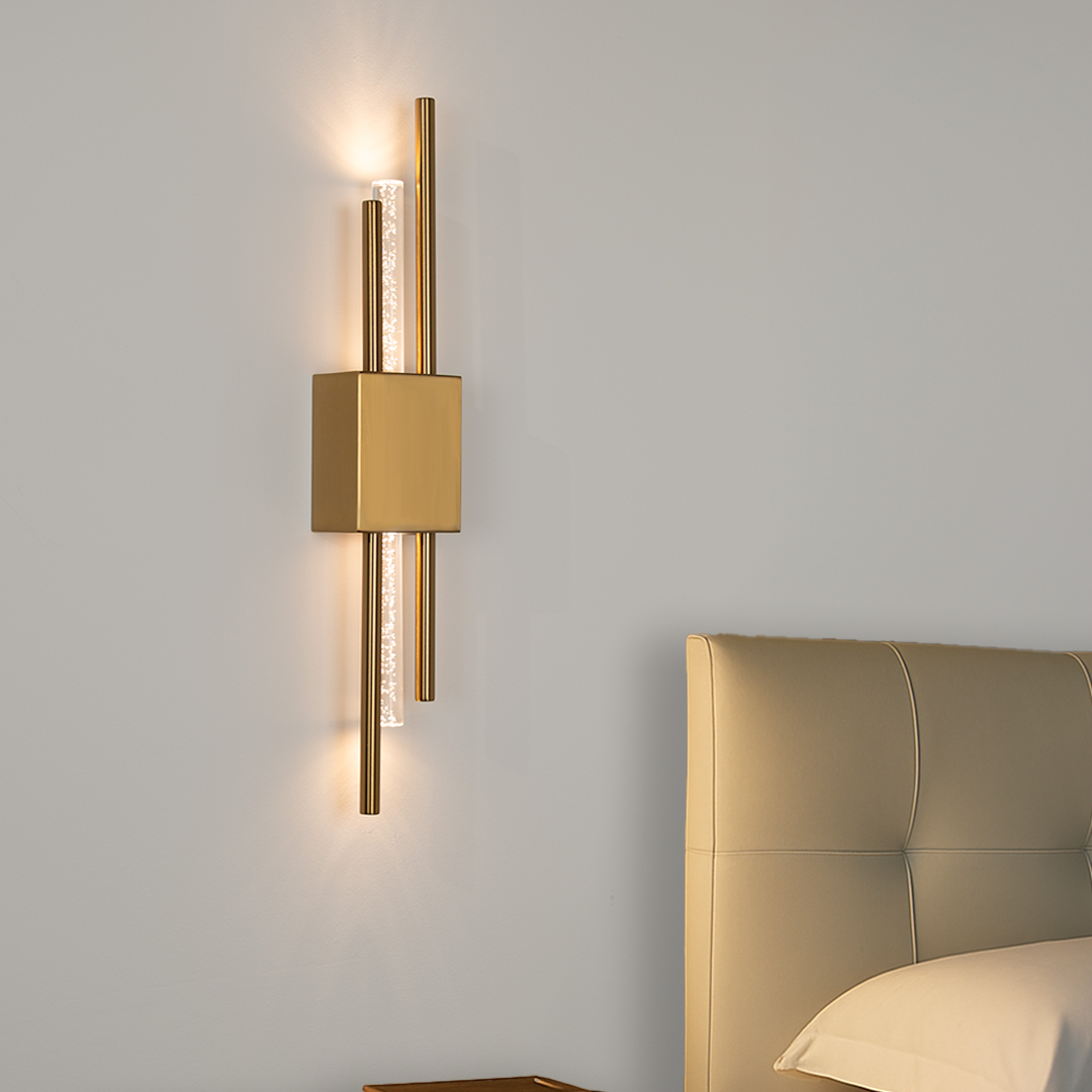 Gold AMBIO rechargeable wall sconce lit beside an upholstered bed, Mistiva