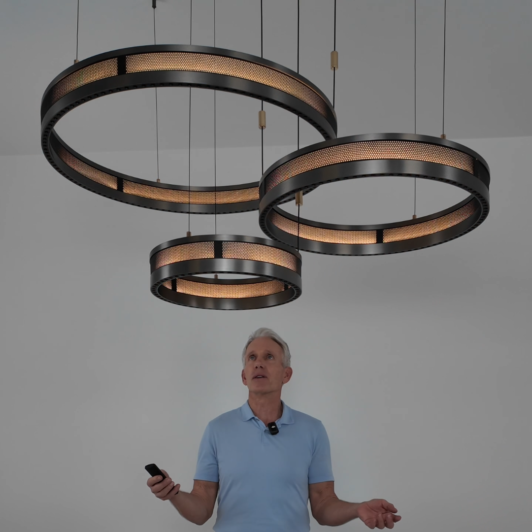 Titan Rings gunmetal ring chandelier, three rings of different sizes hung high in a bright room with a man holding the remote