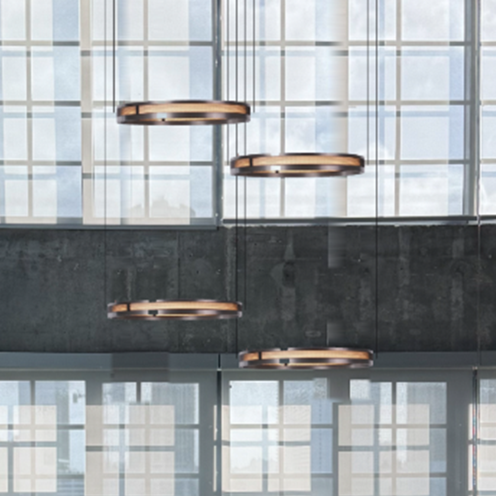 Titan Rings chandelier for high ceilings, four lit rings at staggered heights against a wall of tall windows